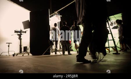 Blurry images of film crew working and filming in video production studio which using equipments such as cinema camera big film light and soft box or Stock Photo