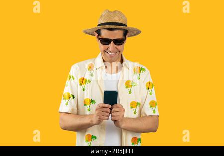 Latin man texting using smartphone over isolated yellow background with a happy face standing and smiling with a confident smile showing teeth Stock Photo