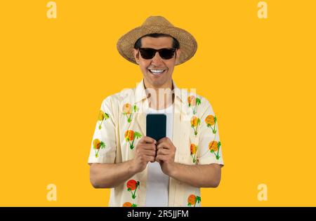 Man texting using smartphone over isolated yellow background with a happy face standing and looking at camera with a confident smile showing teeth Stock Photo