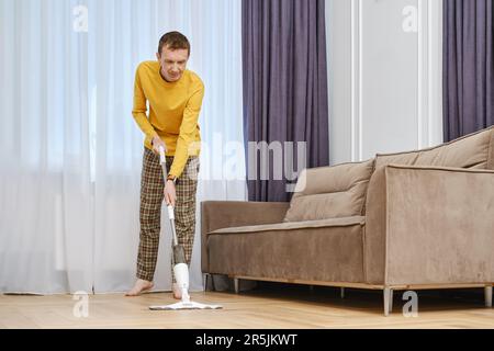Middle age man mopping floors in living room Stock Photo