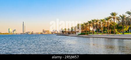 Skyline view of Dubai Creek with palms and skyscrapers from the boat tourist trip. Sunset in sunny summer day. Dubai is famous tourist destination in Stock Photo