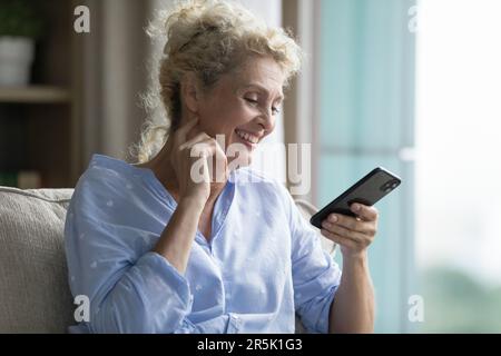 Cheerful pretty blonde mature woman enjoying online communication Stock Photo