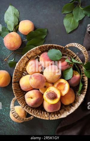 Harvest background. Organic fruits. Farmer's market. Basket of ripe peaches on a stone table. View from above. Stock Photo