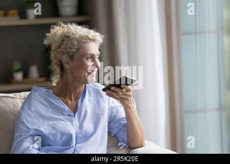 Happy senior mature lady talking on speaker on cellphone call Stock Photo