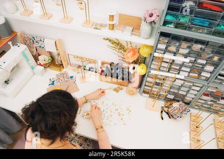 Jewelry designer working in studio, young woman creating handmade earrings, top view Stock Photo