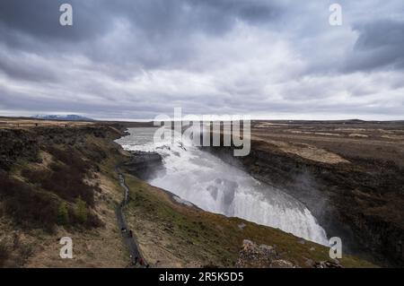 Famous Gulfoss waterfall in the Golden Circle in South Iceland. Tourists walk on a path to the viewpoint. Wide landscape view Stock Photo