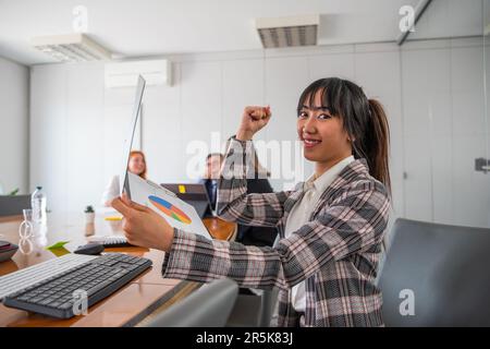 A business woman in the office shows her biceps and is happy with the business results Stock Photo