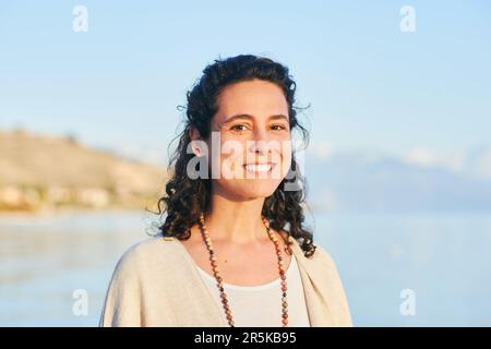 Outdoor portrait of beautiful middle age hispanic woman enjoying nice sunny day by the mountain lake Stock Photo