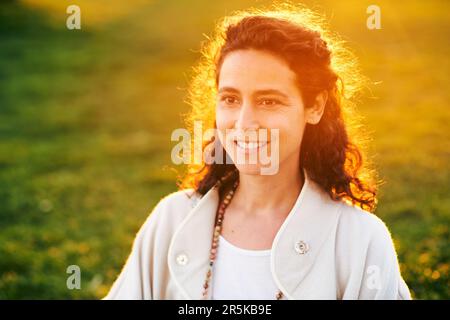 Sunset close up portrait of beautiful mature woman with curly hair Stock Photo