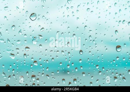 Drops on a window glass with blurry blue background close up , rain macro Stock Photo