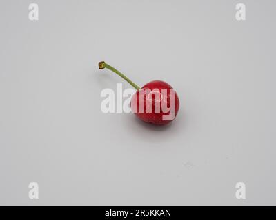 One Juicy, sweet, organic, red cherry glistening with tempting water droplets. Stock Photo