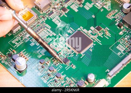 top view, mechanic repairing motherboard, soldering Stock Photo