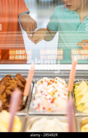 Two children choosing an ice cream flavor in an ice cream shop Stock Photo