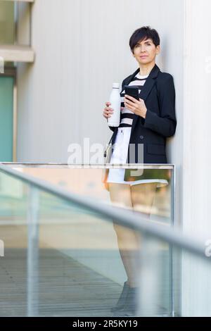 Adult woman using mobile phone while looking away Stock Photo