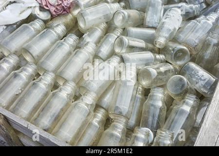 Used empty glass bottles stored for recycling, selective focus. Stock Photo