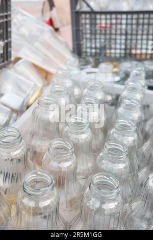 Used empty glass bottles stored in containers for recycling, selective focus. Stock Photo