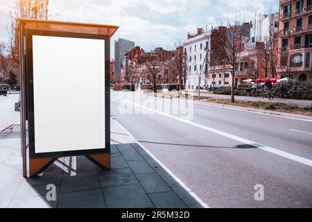 In Barcelona, a picturesque neighborhood is the backdrop for a beautiful sunny day. A white, empty mockup or billboard stands prominently at a bus sta Stock Photo