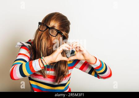 Studio portrait of young girl fooling around, hiding behind, hair, acting silly, time for haircut, hair completely covering the face with glasses over Stock Photo