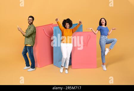 Positive multicultural young friends posing with huge shopping bags Stock Photo