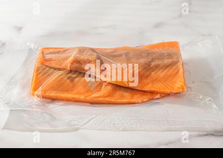 Fresh raw salmon in a plastic bag close-up on marble kitchen table, copy space Stock Photo