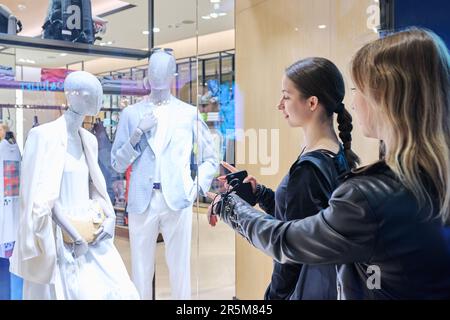 Warsaw, Poland, 12.05.2023. Two young females looking at showcase with clothes in mall Stock Photo