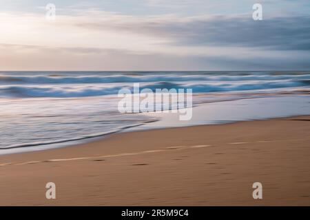 Sunset on the beach. Abstract seascape, soft blurred sea, sand beach, and cloudy sky at sunset Stock Photo
