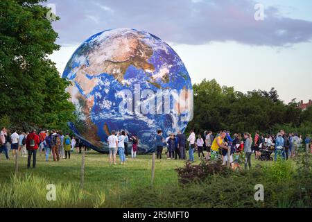 Brno, Czechia - July 12, 2020: People walking in front of inflatable Earth model placed on green grass meadow near planetarium park Stock Photo