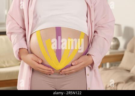 Pregnant woman with kinesio tapes on her belly against white background,  closeup Stock Photo - Alamy