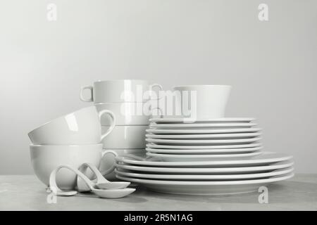 Set of clean dishware on grey table against light background Stock Photo