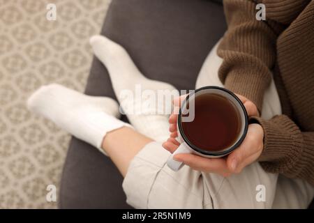 Woman in warm socks relaxing with cup of tea at home, above view Stock Photo