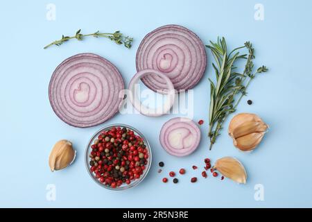 Fresh red onions, garlic, different herbs and spices on light blue background, flat lay Stock Photo