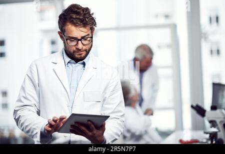 Medicine welcomes the digital age. a focused young male scientist using a digital tablet while standing inside of a laboratory. Stock Photo