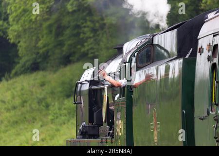 Driver waving goodbye as steam train leaves Horsted Keynes Stock Photo