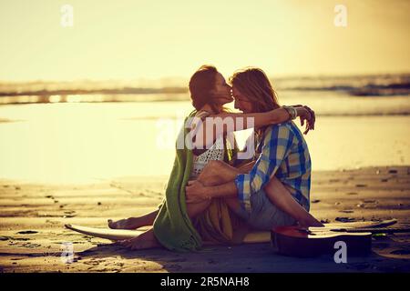 Love is like an ocean, deep and always in motion. a couple sitting on the beach with their legs intertwined. Stock Photo