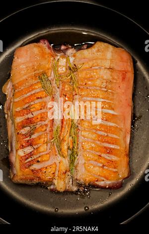 Sliced and seared rack of lamb with rosemary, lying in a pan, food photography with black background Stock Photo