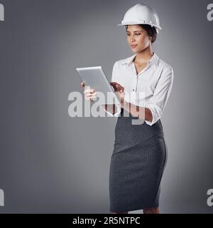 Shes going to exceed their expectatios. a well-dressed civil engineer using her tablet while standing in the studio. Stock Photo