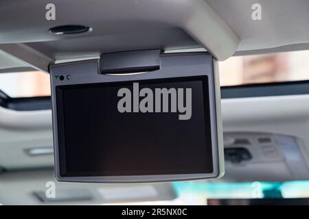 Entertainment system for rear passengers in a car with monitor mounted on the ceiling for watching TV, cartoons and computer games. Stock Photo