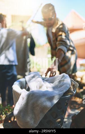 Another one coming up. two cheerful young men doing their washing together outside at home during the day. Stock Photo