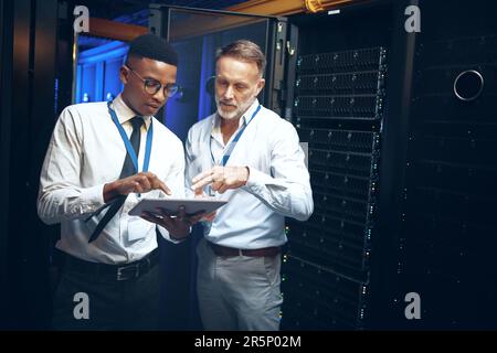 Doing their daily inspections. two technicians using a digital tablet while working in a server room. Stock Photo