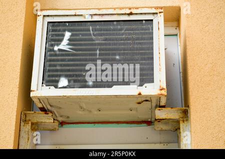 Old bad broken rectangular substandard rusty air conditioner for cooling air in summer. Stock Photo