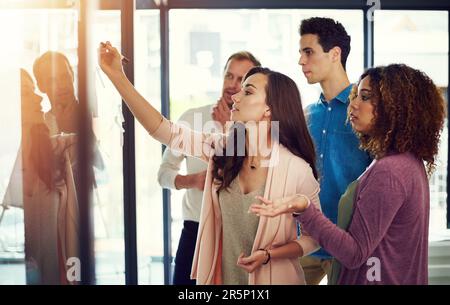 Why dont we try exploring a new option...a group of young designers brainstorming with notes on a glass wall in an office. Stock Photo