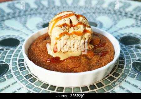 Plate of Warm and Flavorful Skillet Cookie Topped with Ice Cream and Salted Caramel Sauce Stock Photo