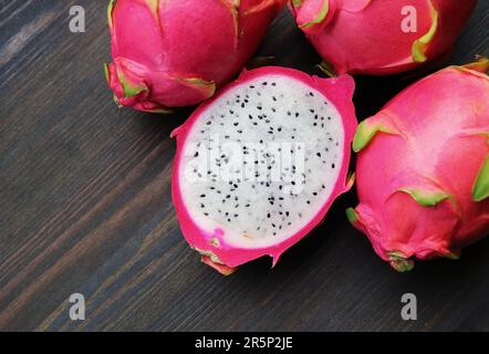 Fresh Ripe Dragon Fruit Cut in Half with Heap of Whole Fruits on Wooden Background Stock Photo
