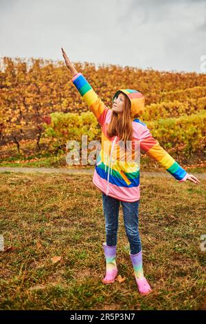 Outdoor portrait of pretty young girl wearing colorful rain coat Stock Photo