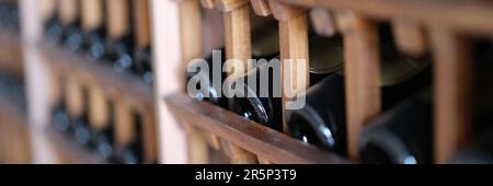 Resting dusty wine bottles stacked on wooden racks in basement Stock Photo