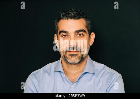 Studio portrait of handsome man wearing formal blue shirt, posing on black background Stock Photo