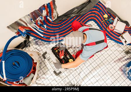 Modern Residential Radiant Floor Heating Pipelines Installation Performed by Professional HVAC Worker Stock Photo