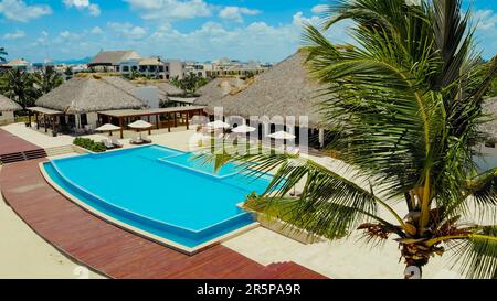 Aerial view of luxury hotel with straw roof villas and pools in ...