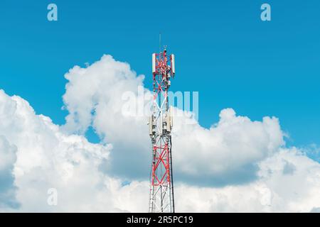 Mobile telephony base station on communication tower against cloudy summer sky Stock Photo