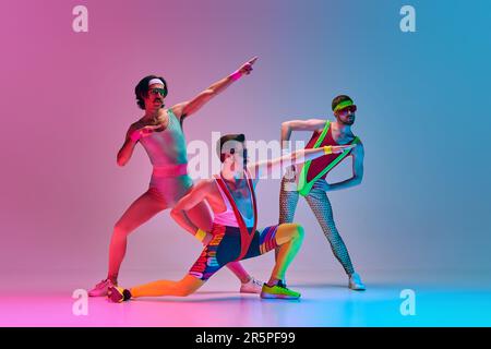 https://l450v.alamy.com/450v/2r5pf99/funny-image-of-three-men-in-stylish-vintage-sportswear-training-aerobics-and-gymnastics-against-gradient-blue-pink-studio-background-2r5pf99.jpg